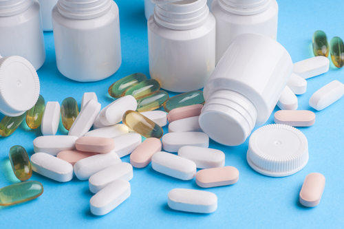 Many pills and tablets isolated on light blue background. Pharmaceutical pharmacology, MAT, medication-assisted treatment.