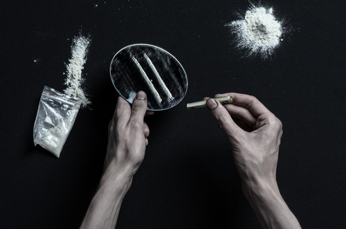 The fight against drugs and drug addiction: hand addict lies on a dark table and around it are drugs.