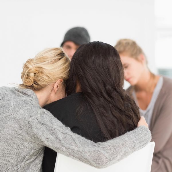 women hugging in rehab group
